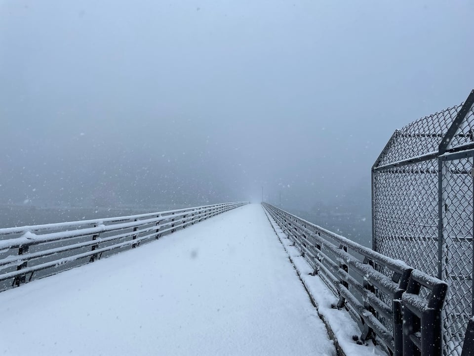 A snow covered bridge leading seemingly to nothing as the heavy snow limits visibility into the distance.