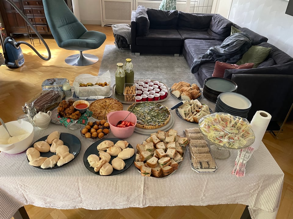 A table filled with treats for and English High Tea - lots of scones, sandwiches, quiches and strawberries.