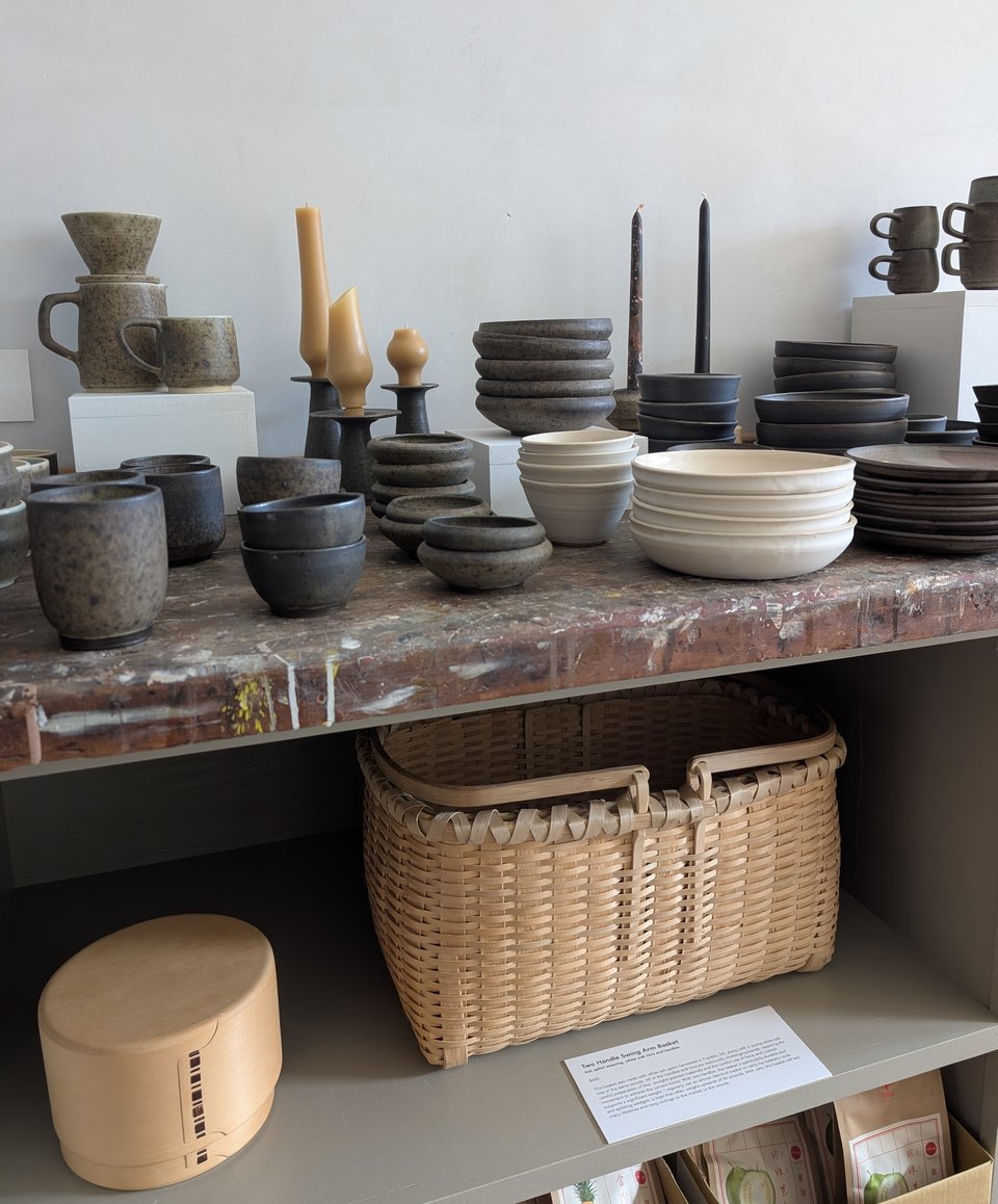 Table with ceramic bowls, cups, magewappa, and basketry