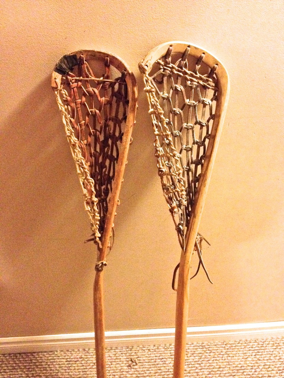 Two wooden lacrosse sticks side by side.
