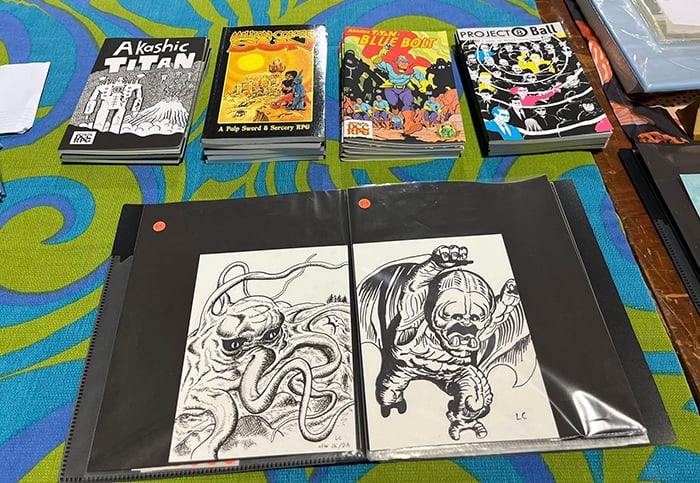 Still yet another shot of my table at space, this time featuring some original art on display, specifically pen-and-ink drawings of the Jack Kirby monsters Sporr and Goom.