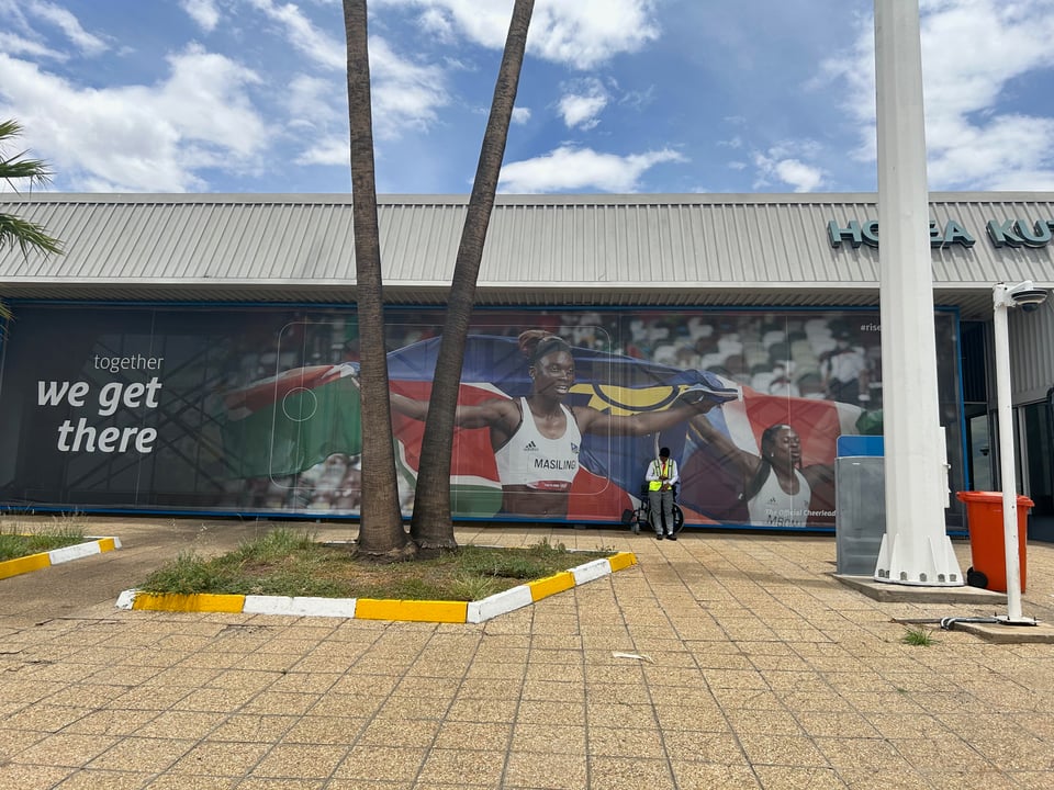 A photo of the side of an airport, which features a big mural of two athletes holding big Namibian flags