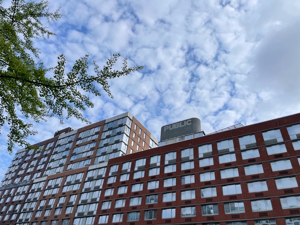 a building with the word PUBLIC at the top behind a clouded sky