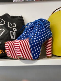 platform high heeled lace up boots covered in red and white stripes and white stars on a blue background, like the American flag
