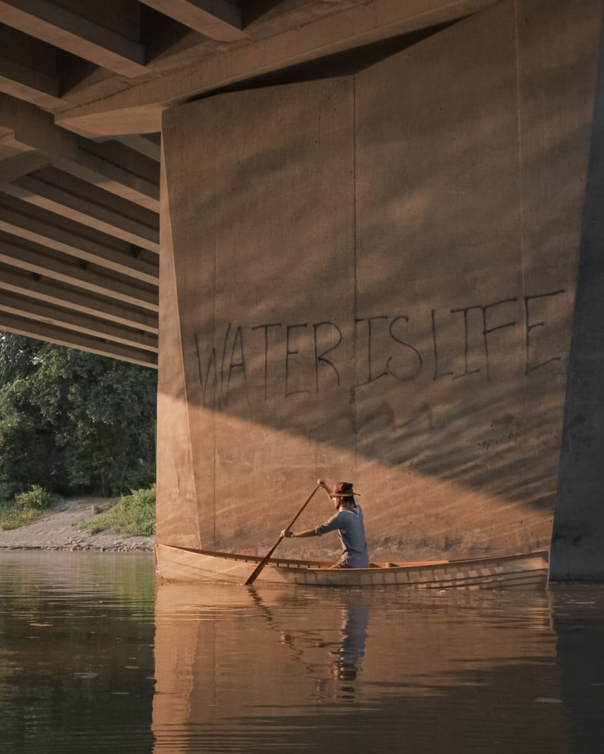 02 - Canoer paddling under Winnipeg bridge