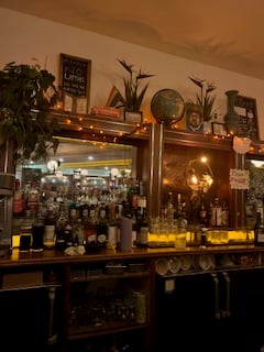 a behind the bar scene of mirrors, bottles, decor, and fairy lights