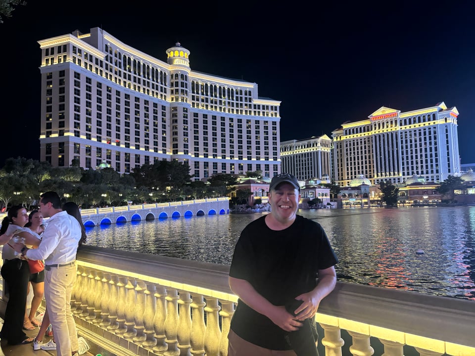 Neil in a black shirt and a bal cao standing in front of the Bellagio Hotel in Las Vegas