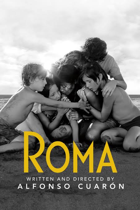 a poster for the film Roma, showing a young woman being embraced by a family, children and a mother, on a beach with the sea behind them