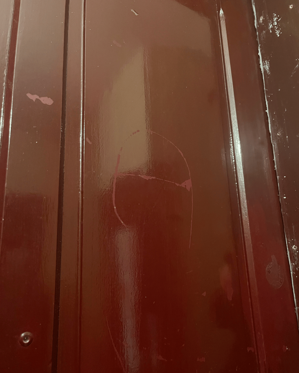Photo of a burgundy door where a scratch really looks like the letter A
