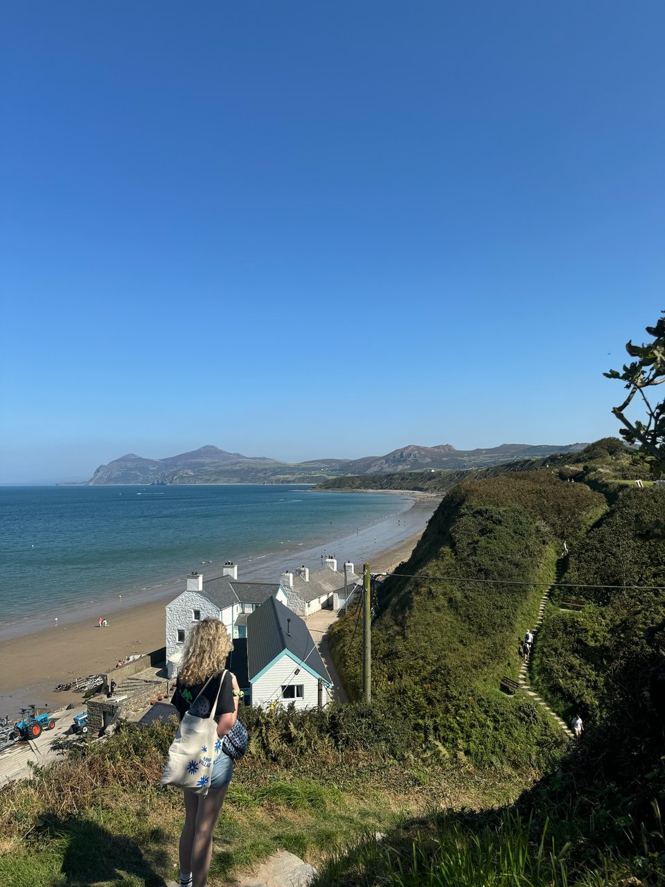 a woman walking down a hill to a beach