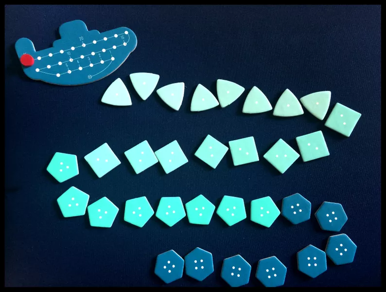The components of the game Deep Sea Adventure are laid out with the submarine at the top and a path of treasure tiles winding down from it