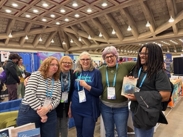 A photo of five smiling people in what looks like a bunker, cement floors and ceiling.