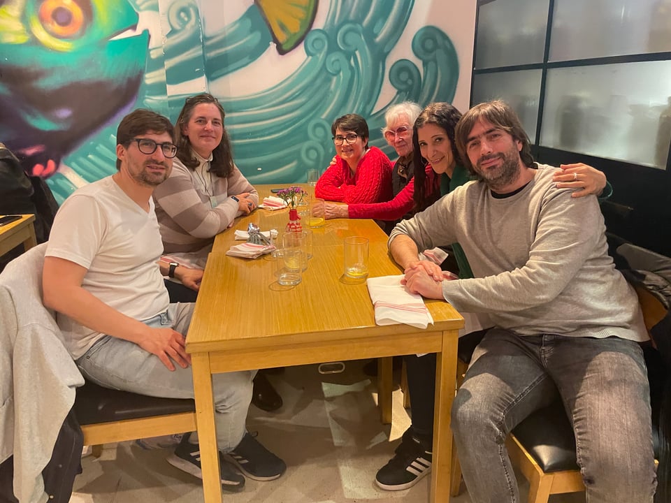Six people sit around a table after dinner.