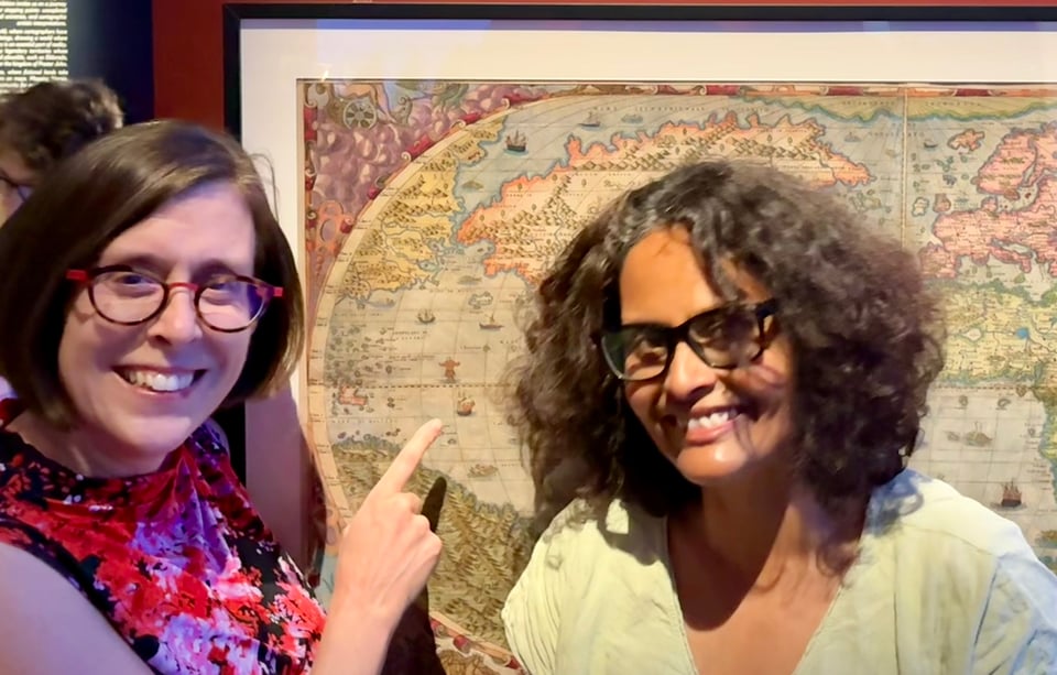 Me and Lisa on either side of a large Renaissance printed map, giggling. Lisa’s pointing at a small detail in the middle of the ocean.