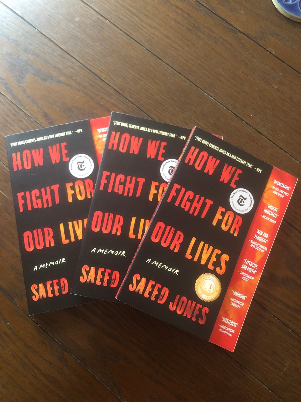 three copies of HOW WE FIGHT FOR OUR LIVES: A MEMOIR by Saeed Jones lie on a tabletop