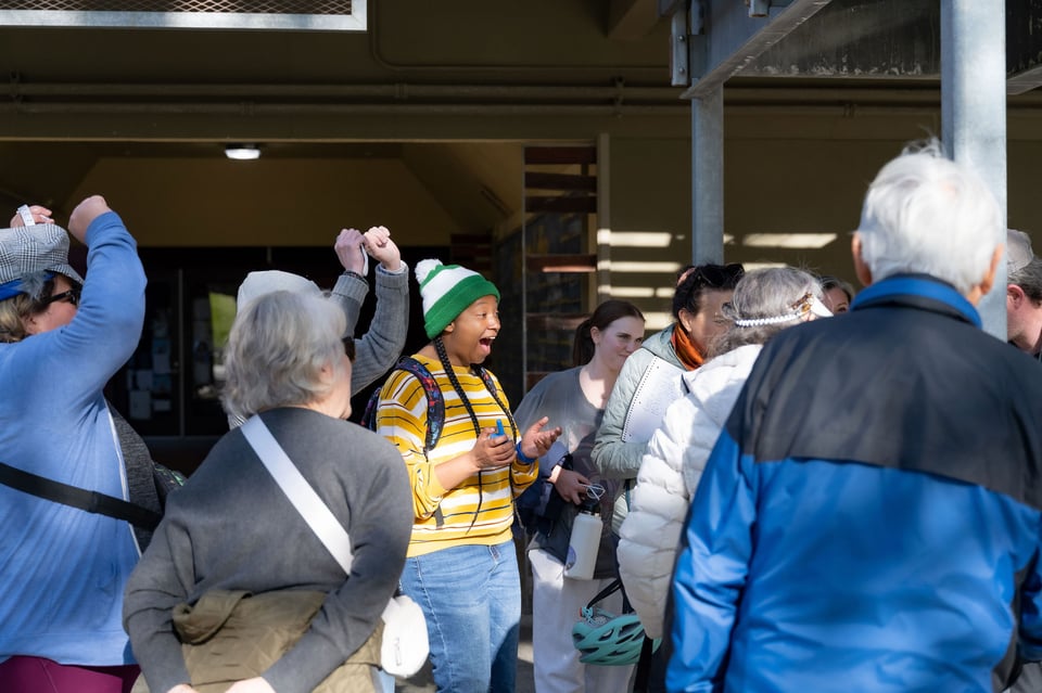 A young black woman in a beanie laughing out loud in a group of people