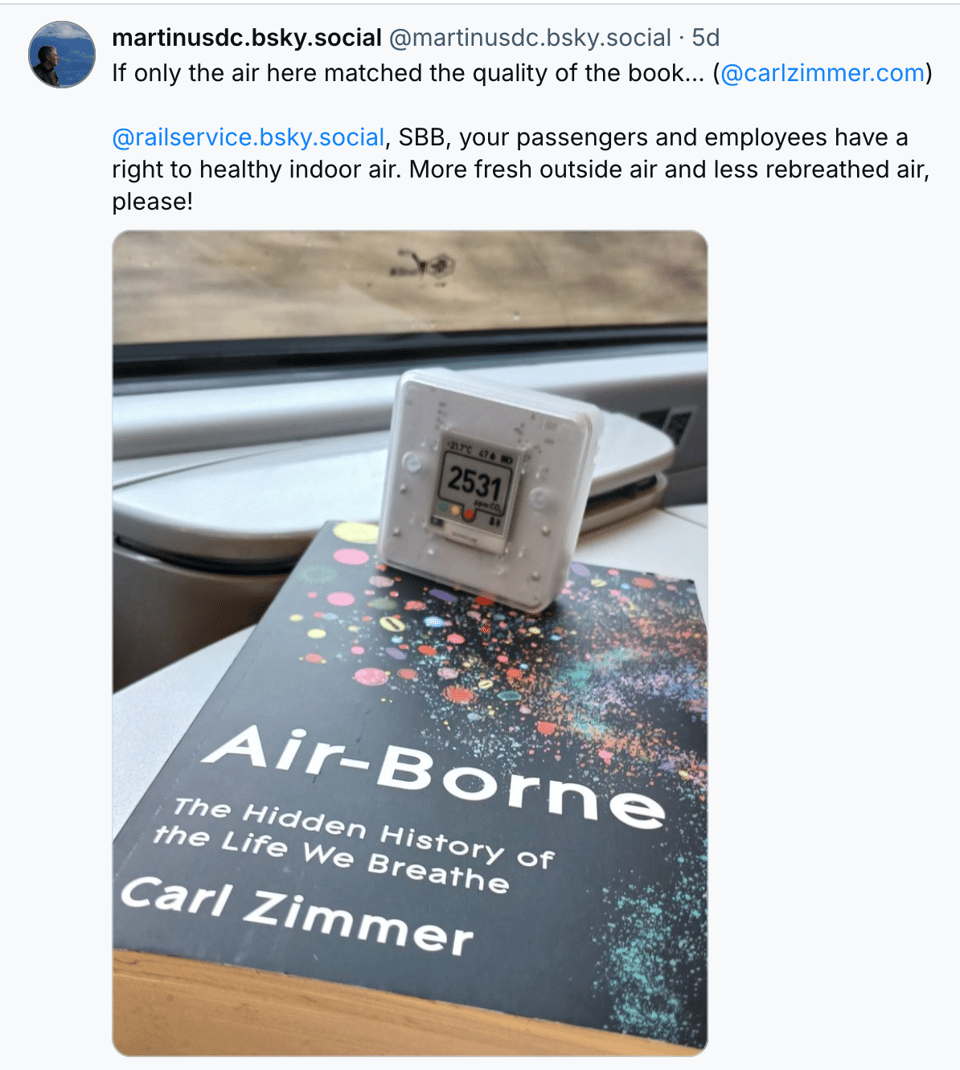 Bluesky post with a carbon dioxide monitor atop my book Airborne. Post reads, "If only the air here matched the quality of the book... ( @carlzimmer.com )  @railservice.bsky.social , SBB, your passengers and employees have a right to healthy indoor air. More fresh outside air and less rebreathed air, please!"