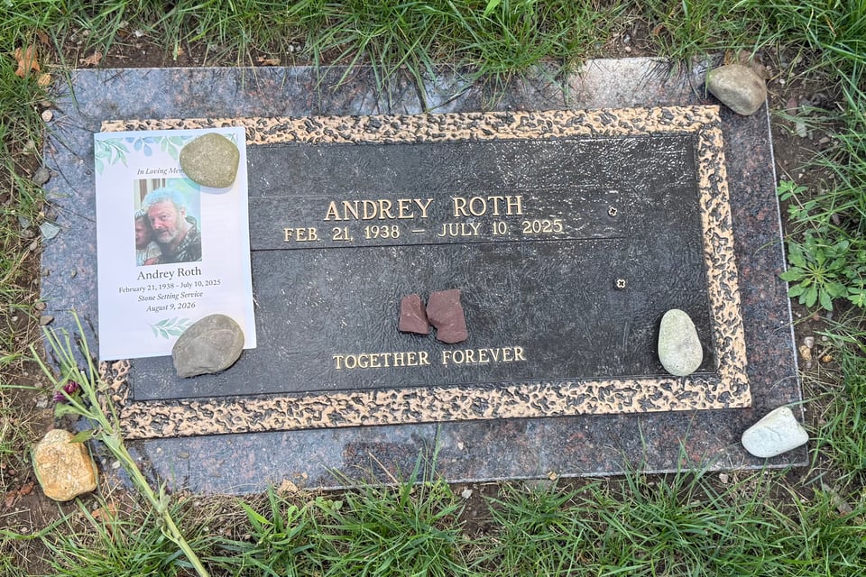 photo of a grave marker with stones and a pamphlet on it; the marker reads, "ANDREY ROTH
FEB. 21, 1938 - JULY 10, 2025
TOGETHER FOREVER"
with a gap between the second and third lines, awaiting the inclusion of another person's dates