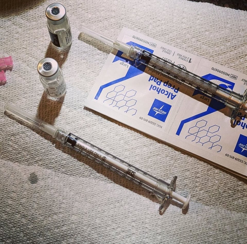 Two empty glass vials of Ilaris with two empty syringes next to them