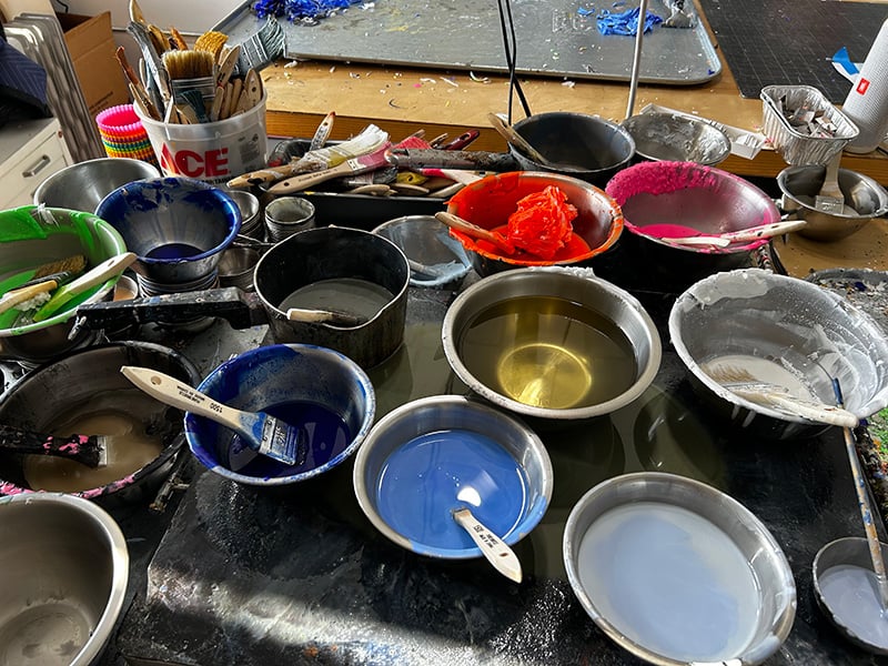 Lots of metal pans, filled with wax of various colors, with paintbrushes in them, warming on a hot plate. And some electrical wires dangerously close to the hot plate. That's not smart.