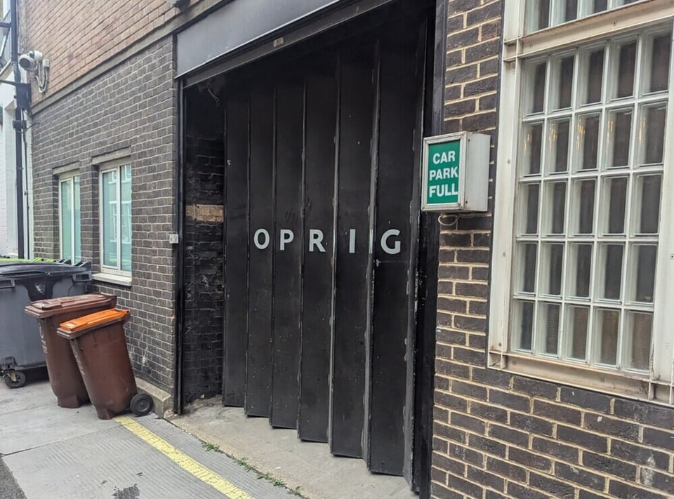 A door with OPRIG written on it due to the perspective on a NO PARKING sign.