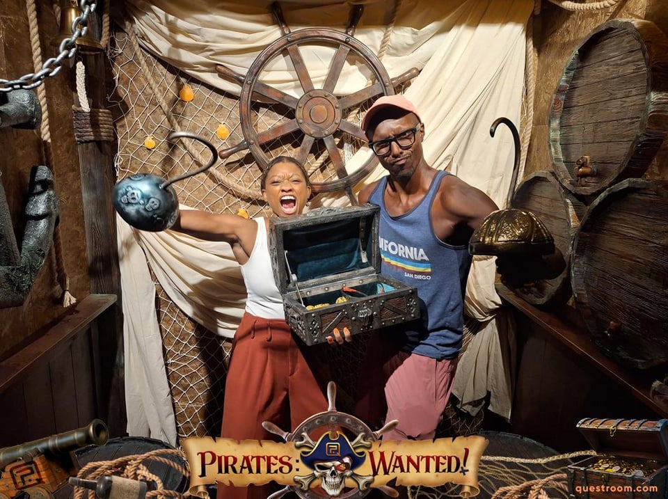 Rob and Nadia make faces at the camera holding onto a chest of gold and with their free arms as hooks.