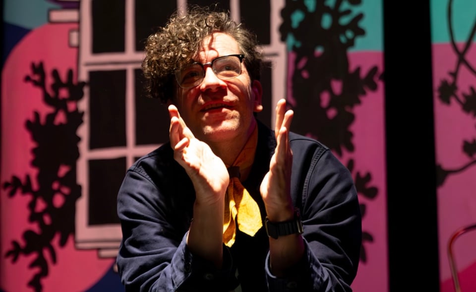 roy on stage in dramatic lighting, kneeling and praying in the middle of a scene.