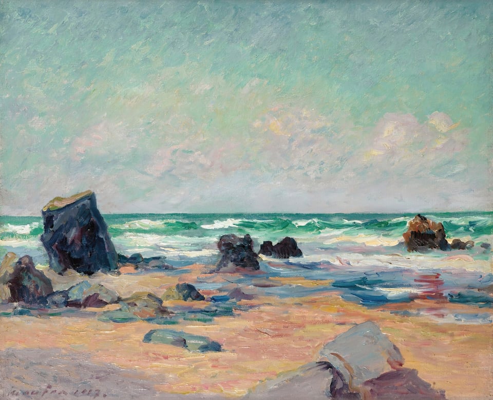 Black rocks on a yellow sand beach. In the background turquoise and white sea waves.