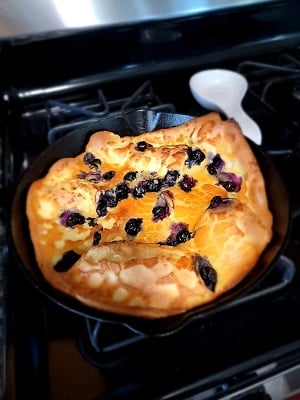 Blueberry Dutch baby in a cast iron skillet on the stove