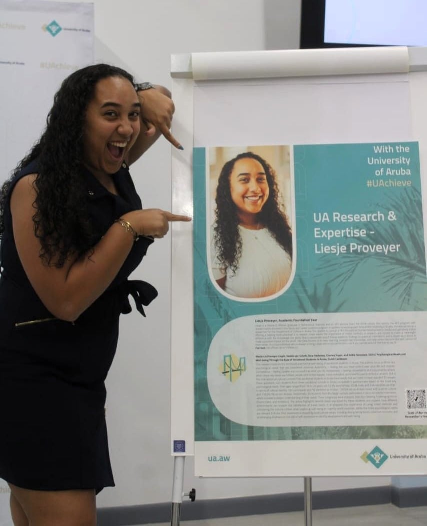 Liesje Proveyer pointing towards her UA Expertise poster, where she is highlighted as a researcher and a summary of her recent article is outlined.