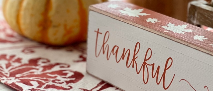 a wooden sign with the word thankful next to a pumpkin