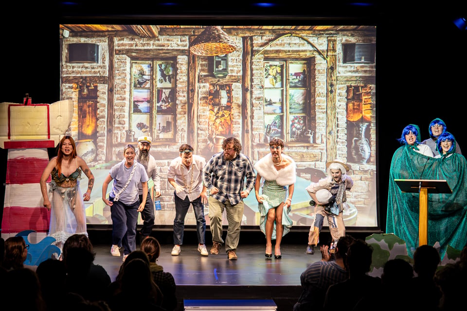 the cast of airhorn mid-dance in front of a tavern backdrop