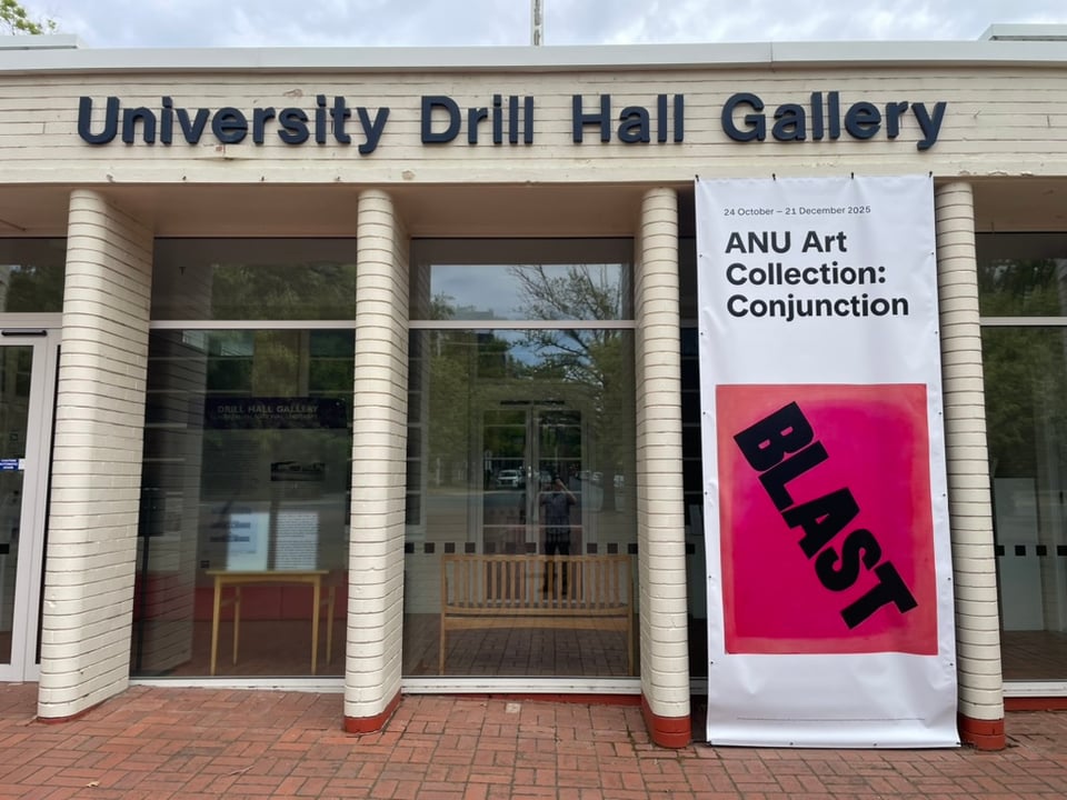 Photo of entrance to the Drill Hall Gallery displaying Chris Carmody's painting titled BLAST/BLESS