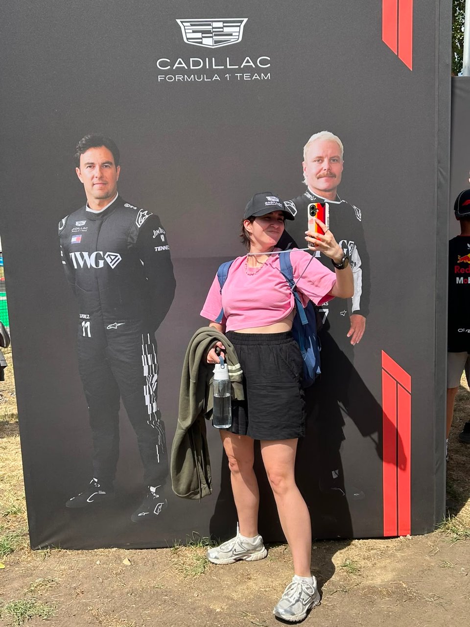 A woman taking a selfie with Cadillac F1 drivers