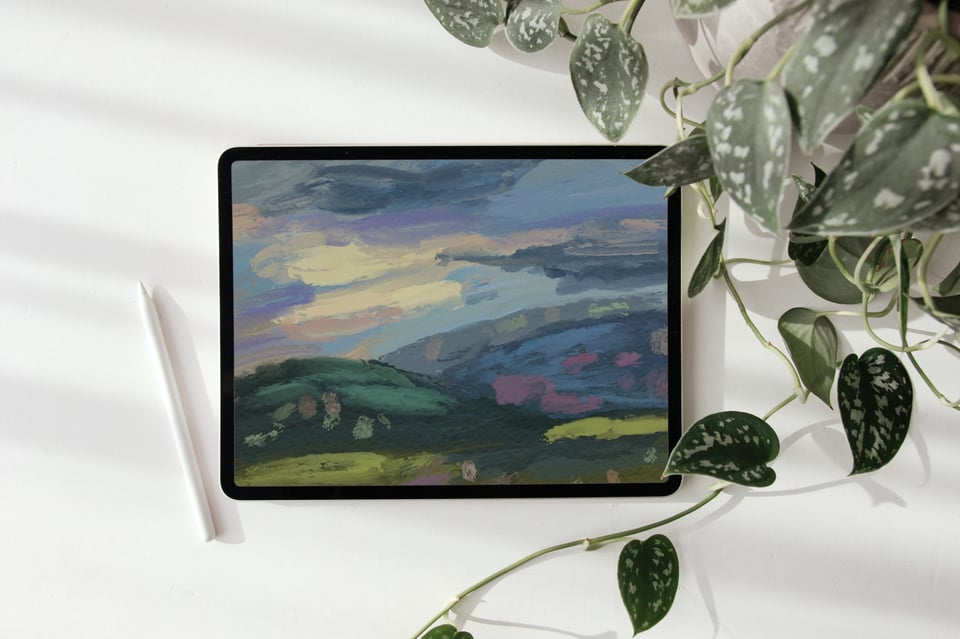 A photo of an iPad with a lock screen of a blue themed expressive Puerto Rican landscape. An Apple pencil and a vine plant border the tablet.