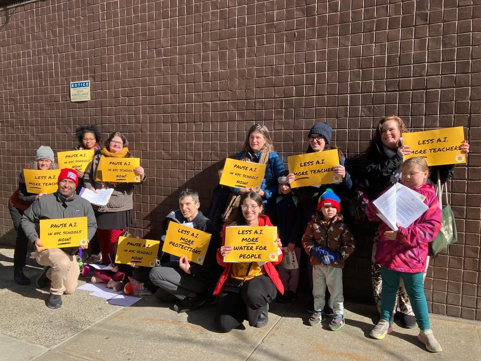A bunch of folks, young and old, holding up signs that say things like "Less AI, More Water for People."