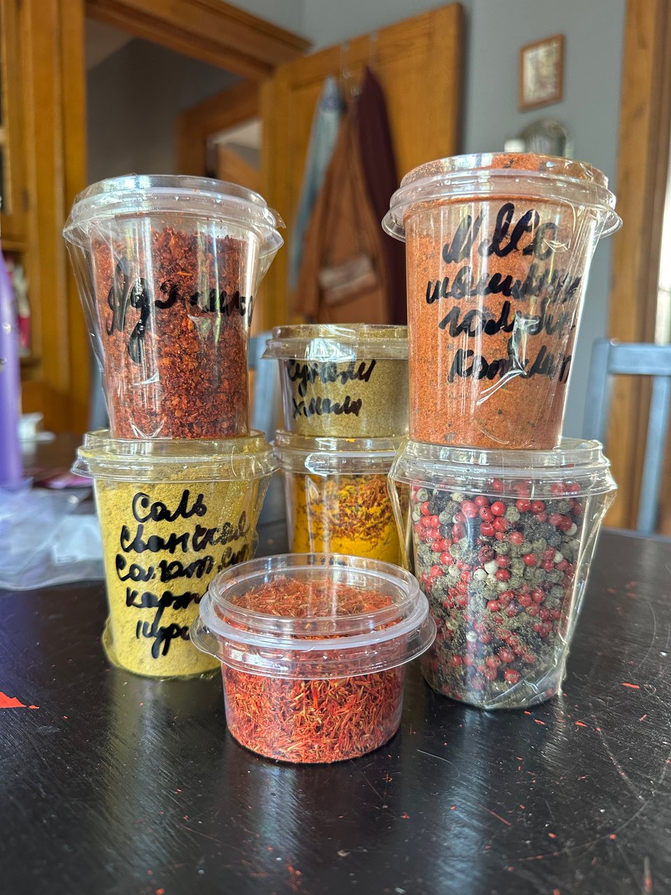 An array of spices in plastic containers with handwritten Russian labels