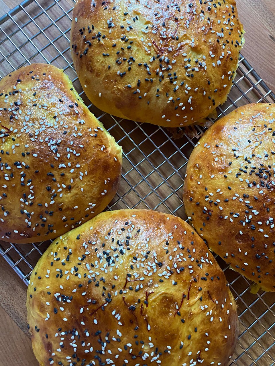 Four round breads colored yellow by saffron and clicked with black and white sesame seeds.
