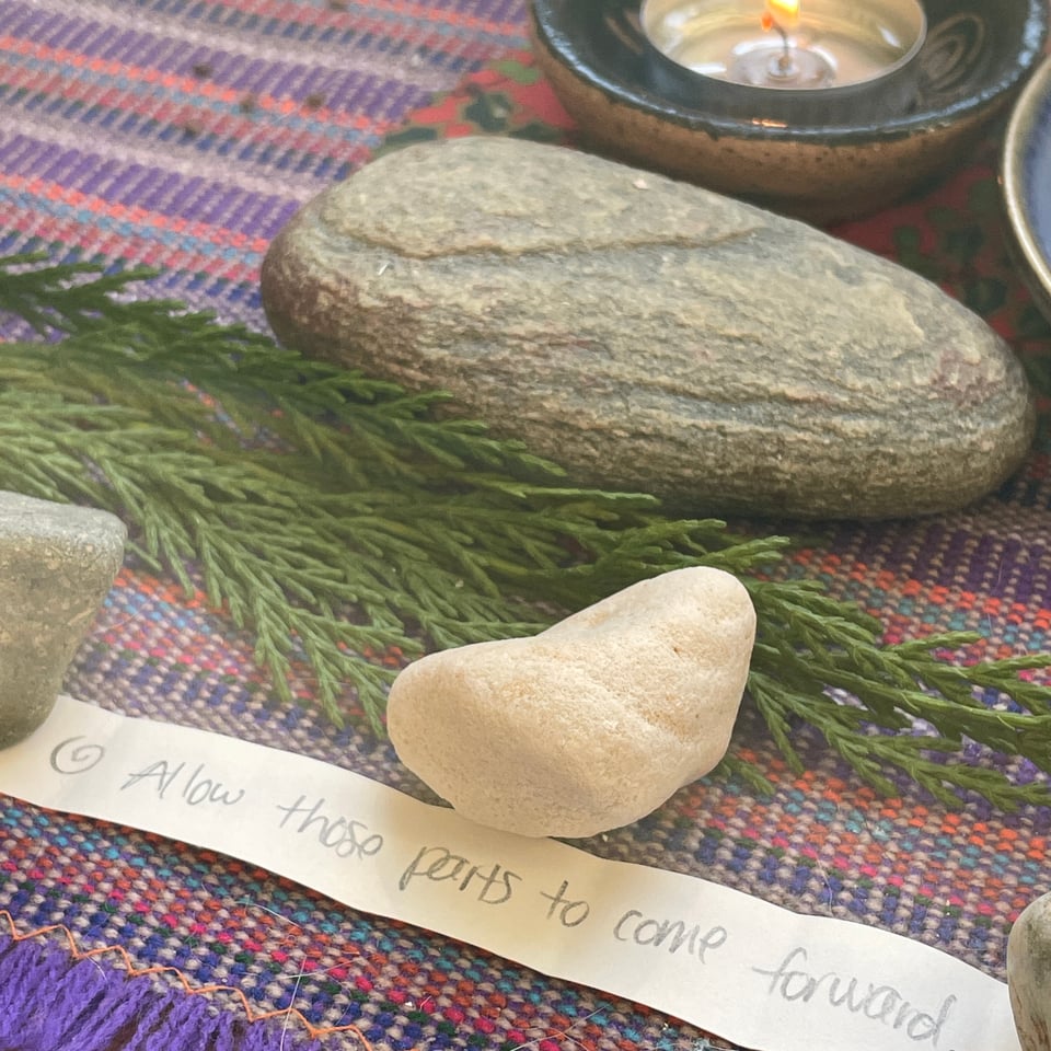 image of an altar space with a piece of paper that says, "allow those parts to come forward" with rocks and some foliage