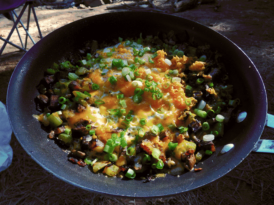 A pan of breakfast mash topped with cheese and sliced green onions.