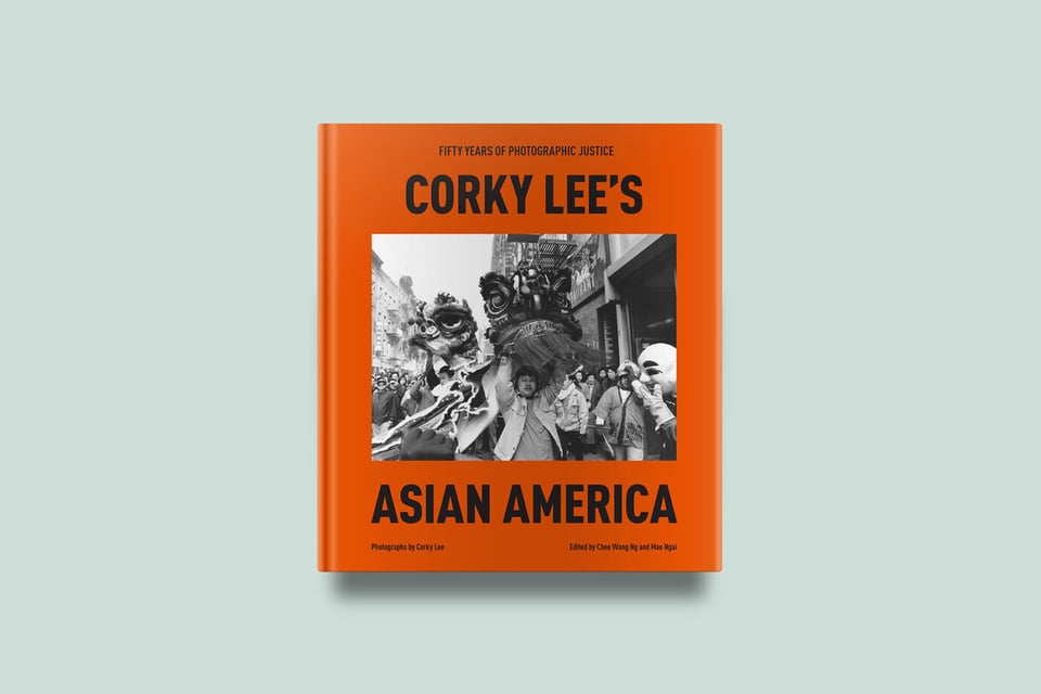 A photograph of the cover of Corky Lee's Asian America, an orange book with a black and white photograph of a Chinese American Lion dancer in the center.