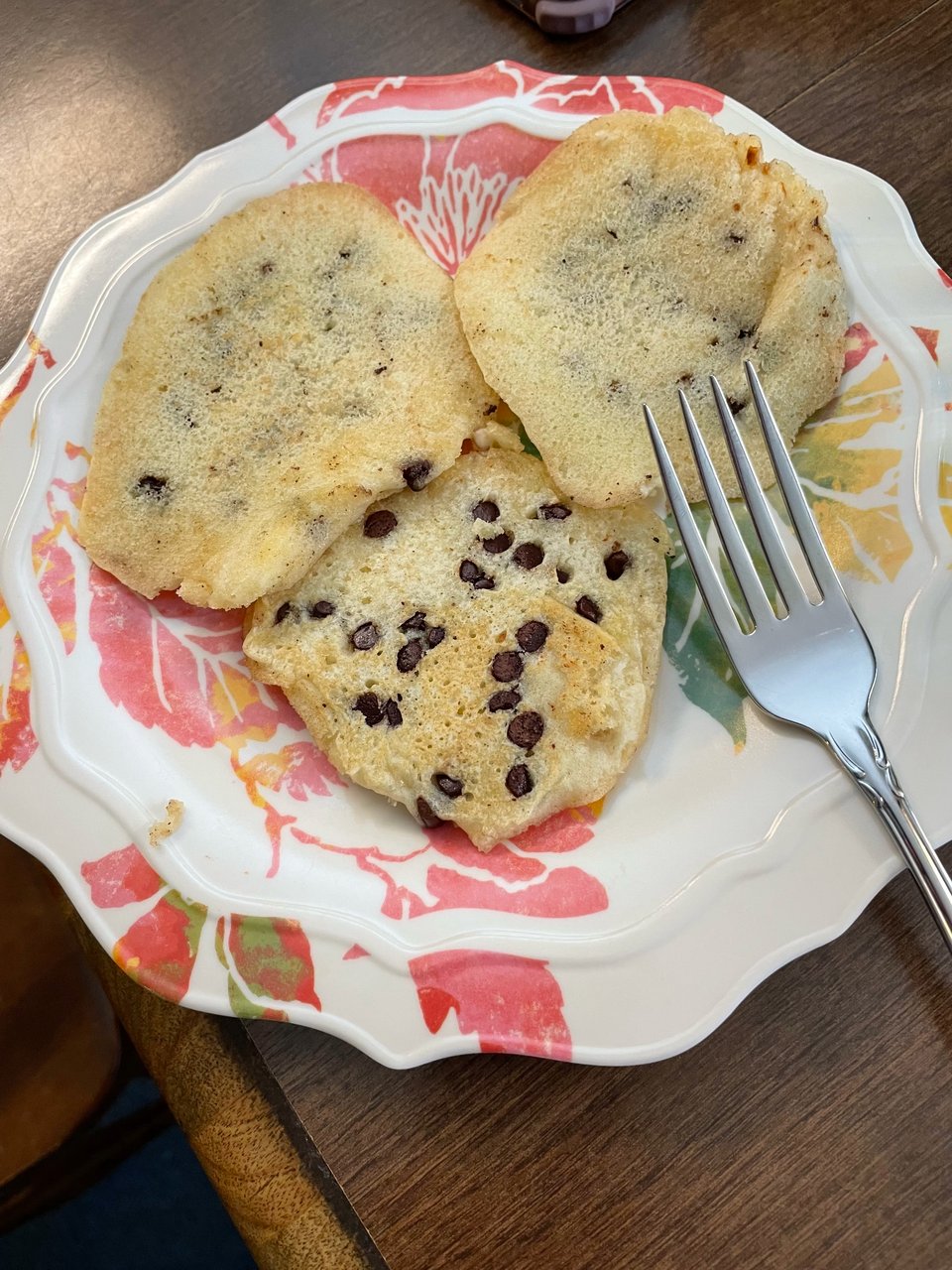 Three small pancakes on a plate with a fork