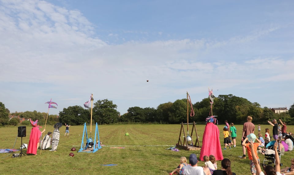 A park with people crowded around two wooden trebuchets