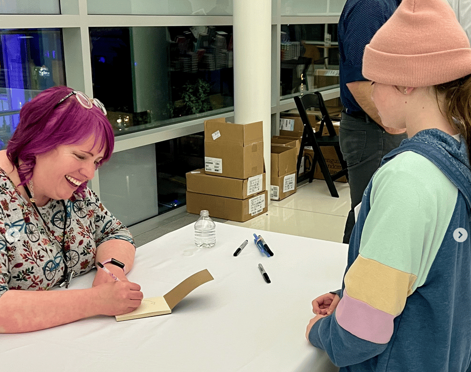 Yours truly drawing a little doodle in a young fan (also named Sarah!)'s sketchbook