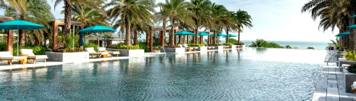 a swimming pool with lounge chairs and umbrellas