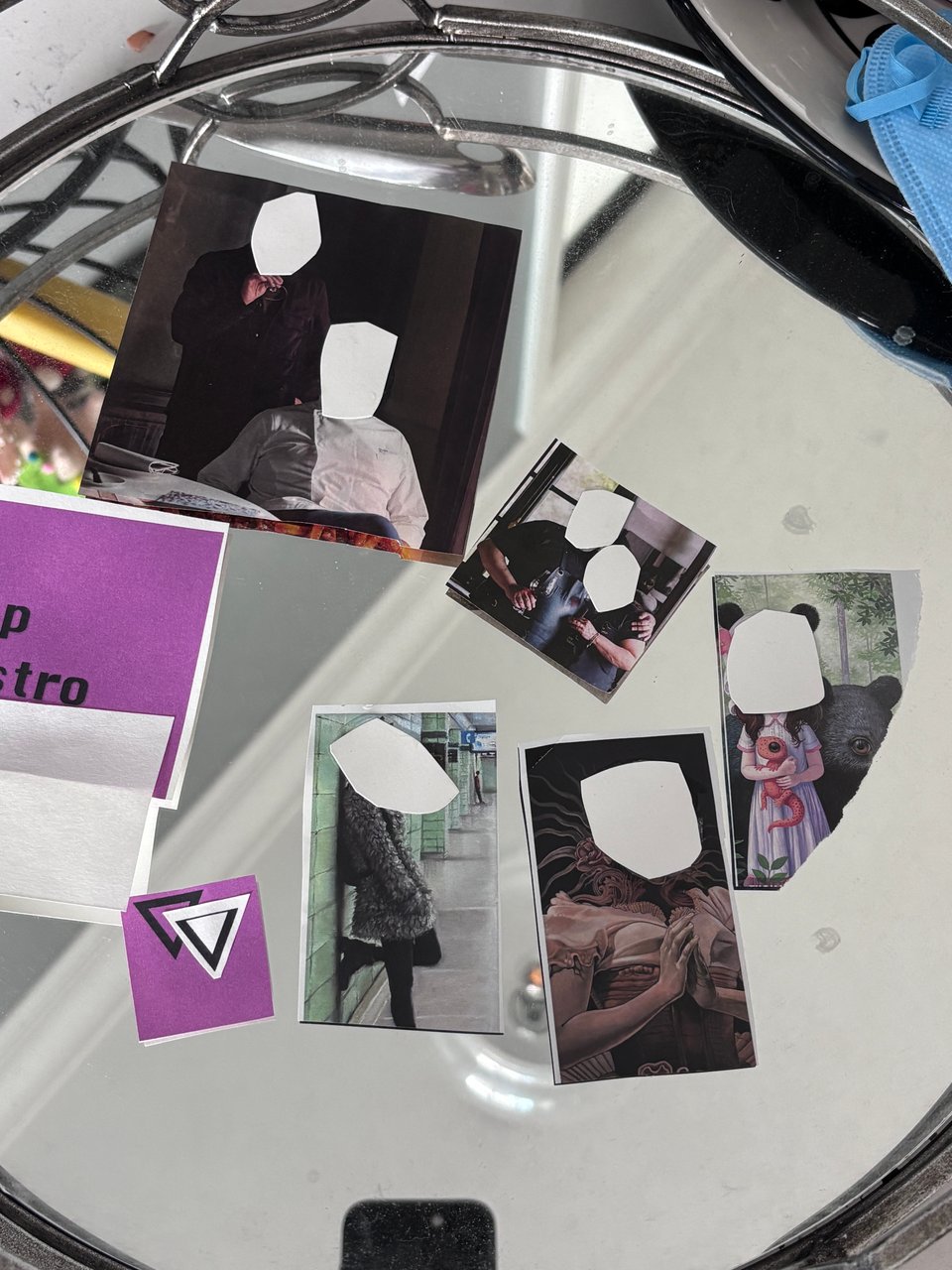 An assortment of collages laid across a mirrored surface. The collages mostly depict people whose faces are whited out with a white oval.