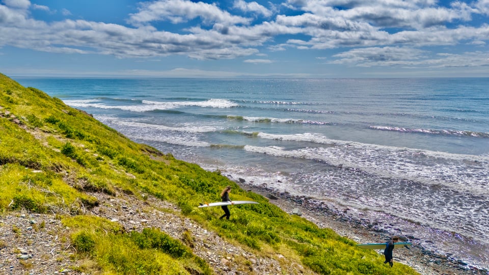 me and shane walk down a cliff side to surf some waves