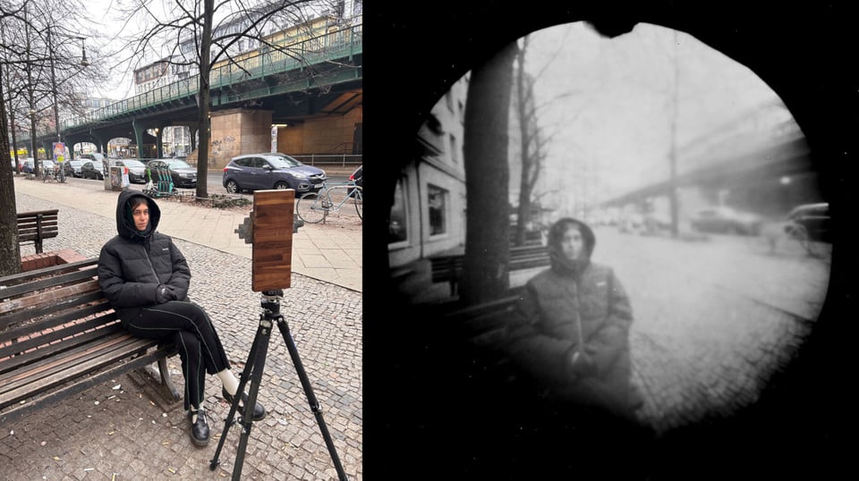 On the left, a woman sitting on a bench in a warm coat with the hood pulled over her head, looking at a camera apparatus on a tripod. On the right, the photo of the woman, looking like an old fahioned pinhole camera, black and white and very fuzzy, like something from 1900