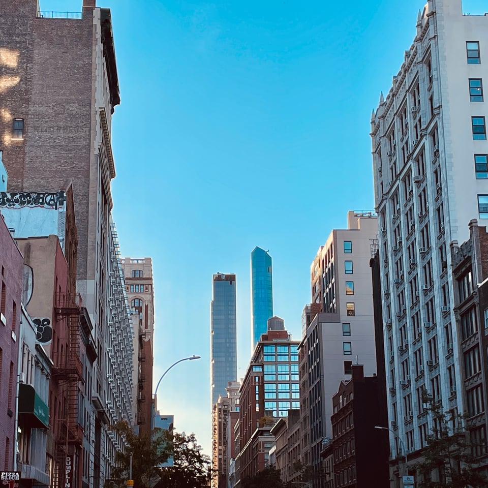View of 23rd st looking east, sun making very brilliant outlines on tall buildings and brilliant blue sky.