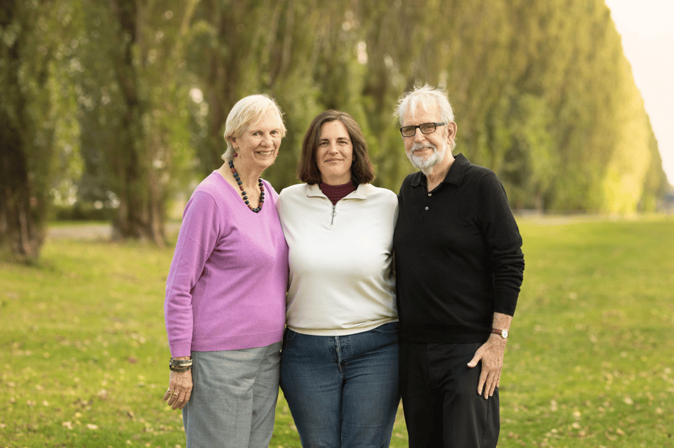 Three people stand next to each other in the middle of a park.
